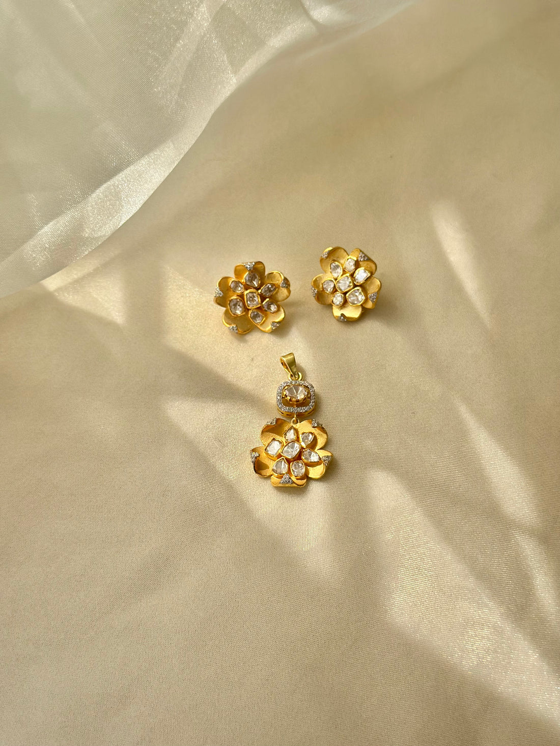 Kusum Polki Earrings featuring sculpted gold-tone flower petals with clustered clear-stone centres.