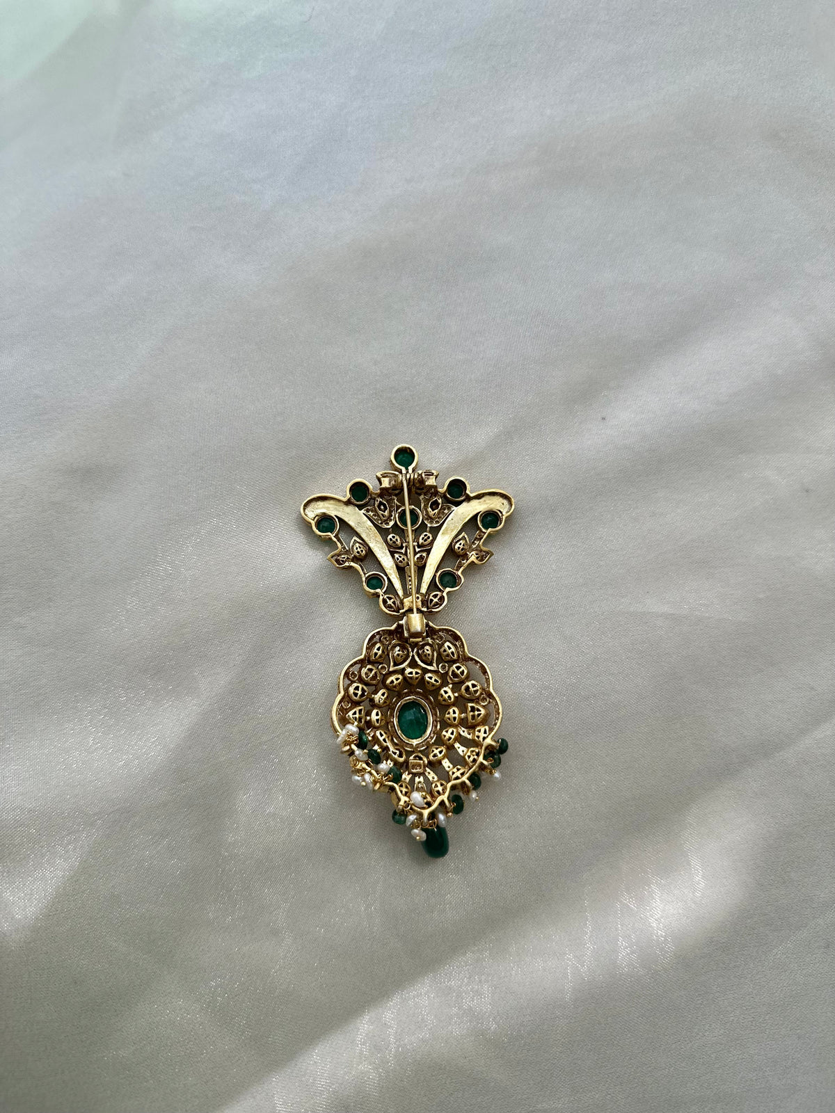 Kochi Brooch featuring green accents, clear-stone detailing and a dangling green bead in an ornate gold-tone setting.