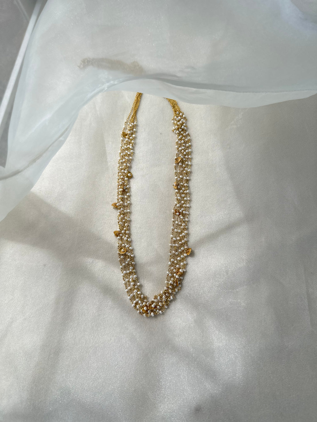 Gigi Necklace featuring layered strands of small white beads with gold-tone accents