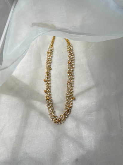 Gigi Necklace featuring layered strands of small white beads with gold-tone accents