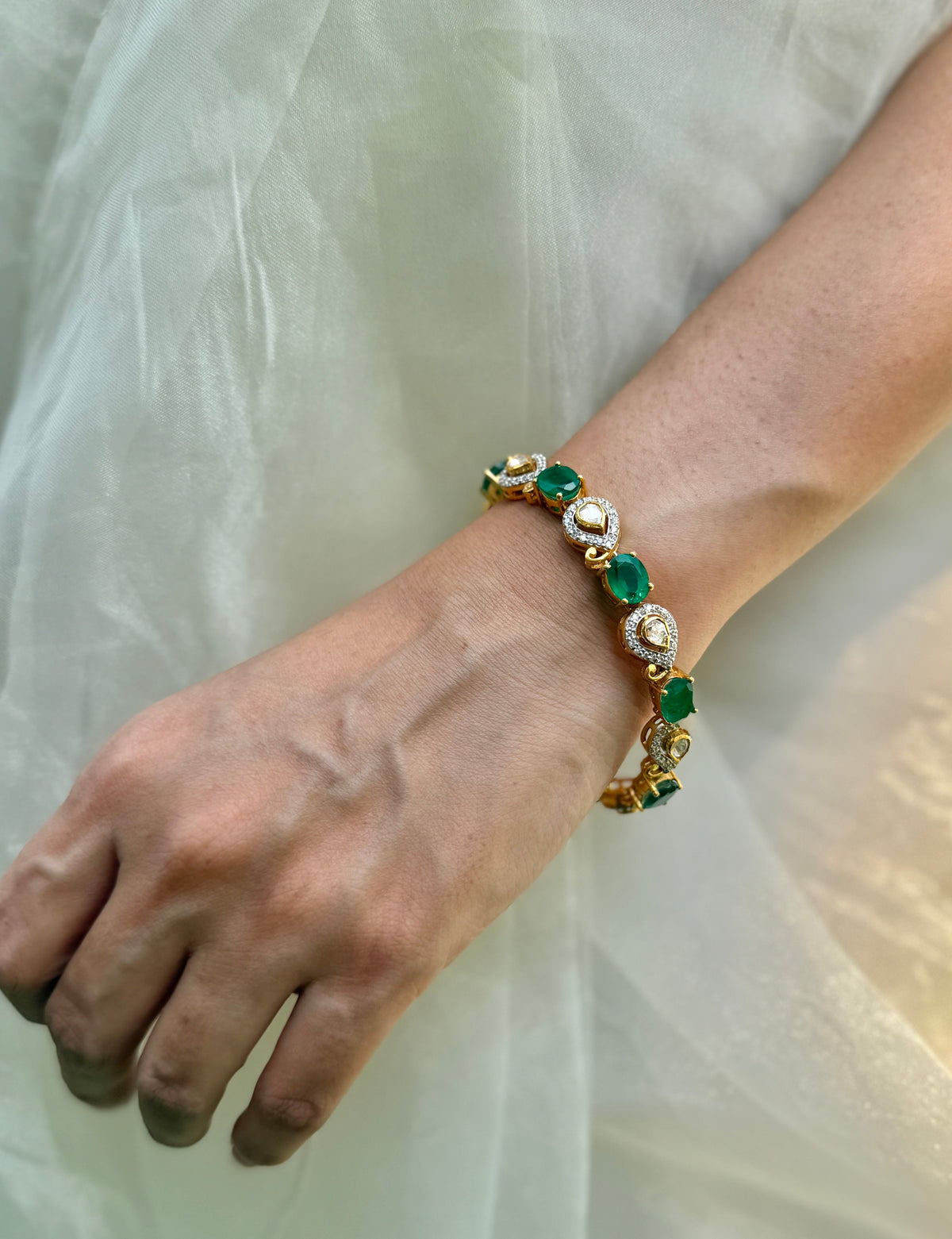 Arzaana Bracelet featuring alternating green oval stones and clear teardrop links in gold-tone settings