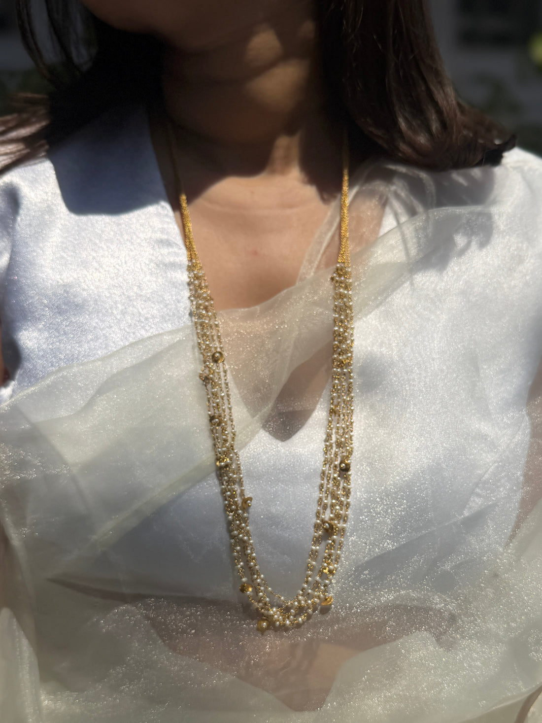 Gigi Necklace featuring layered strands of small white beads with gold-tone accents