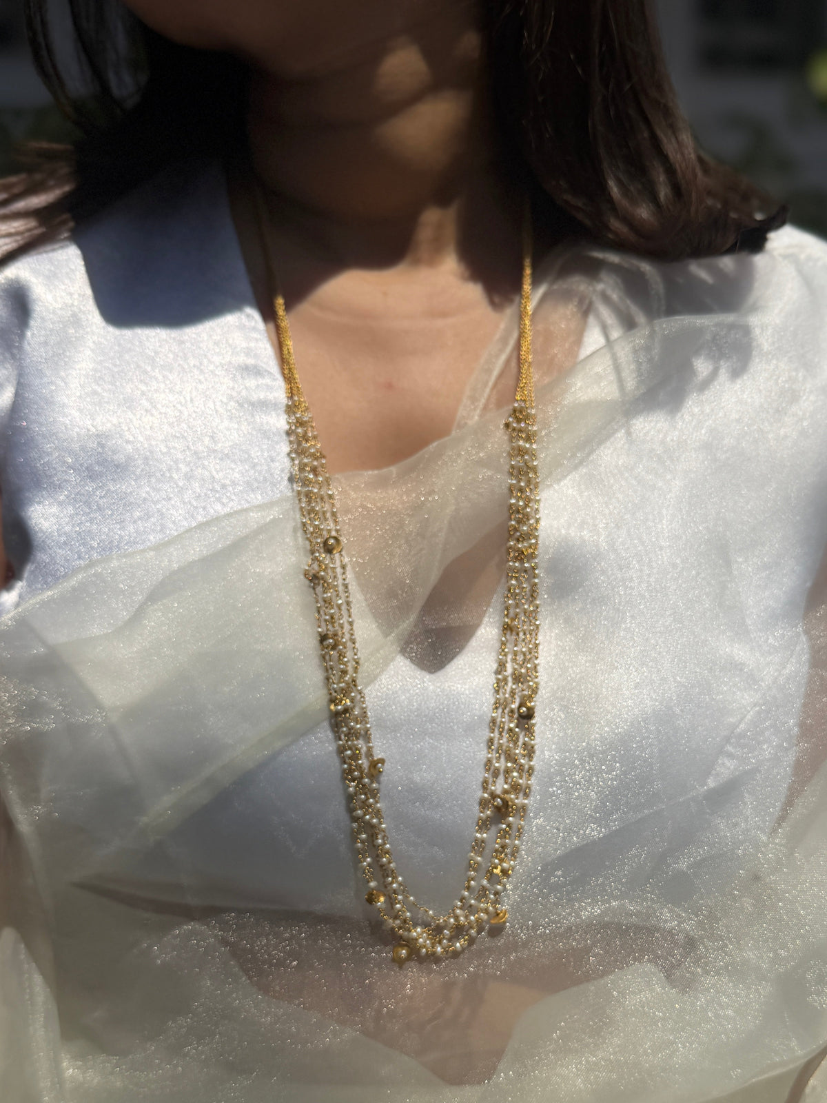 Gigi Necklace featuring layered strands of small white beads with gold-tone accents