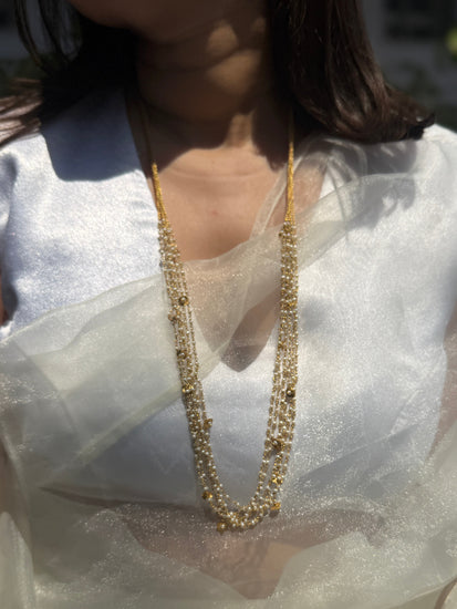Gigi Necklace featuring layered strands of small white beads with gold-tone accents