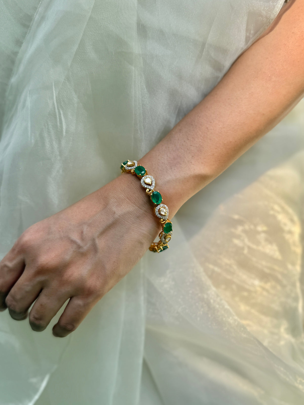 Arzaana Bracelet featuring alternating green oval stones and clear teardrop links in gold-tone settings