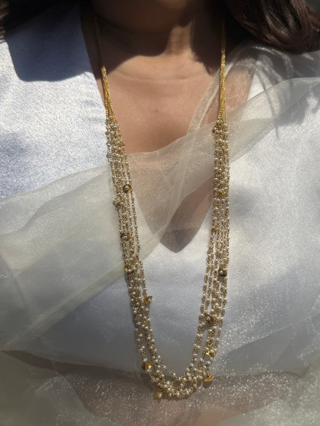 Gigi Necklace featuring layered strands of small white beads with gold-tone accents