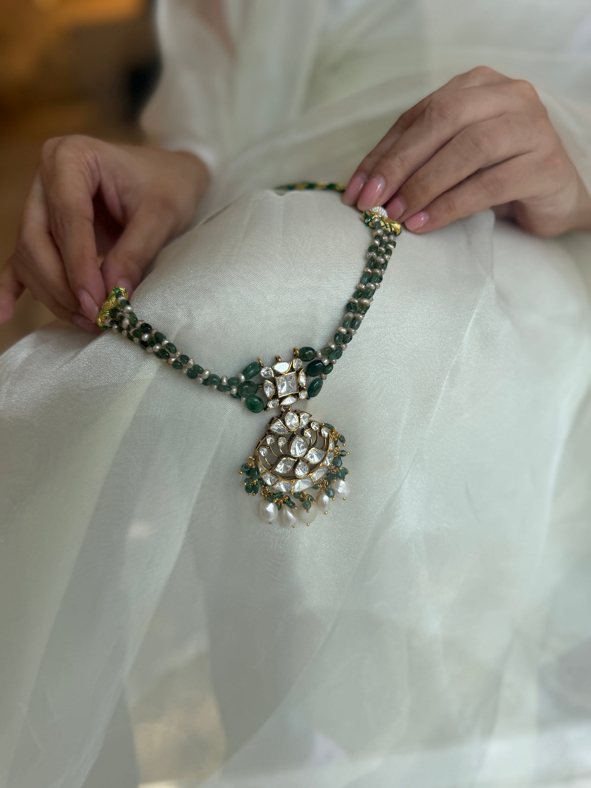 Arohi Necklace featuring green beads, a clear-stone statement pendant and dangling white beads in gold-tone settings.