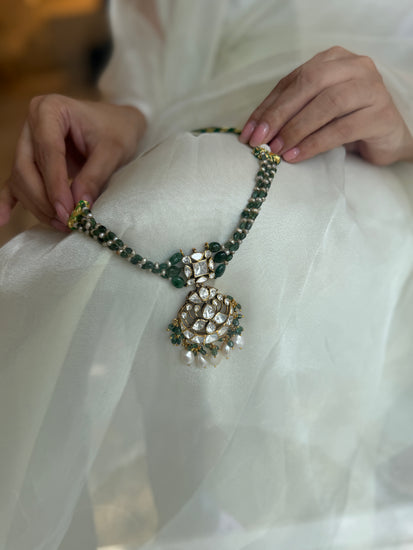 Arohi Necklace featuring green beads, a clear-stone statement pendant and dangling white beads in gold-tone settings.