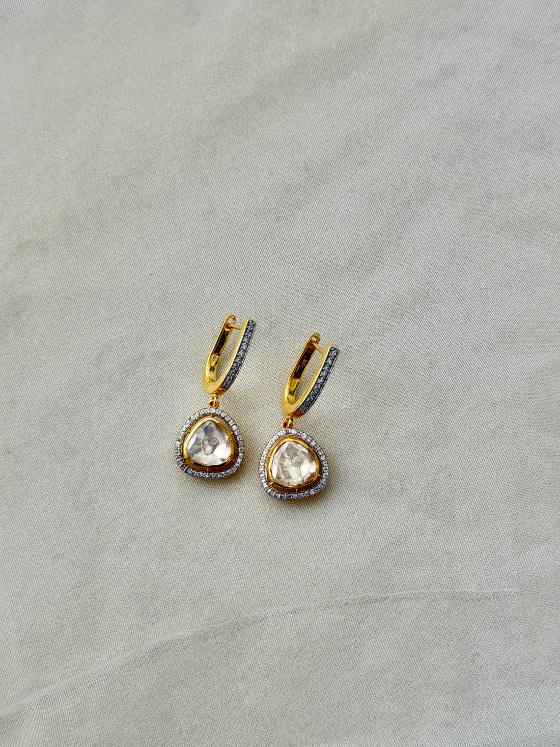 Tilak Earrings featuring clear triangular drops with sparkling stone borders suspended from gold-tone hoops.