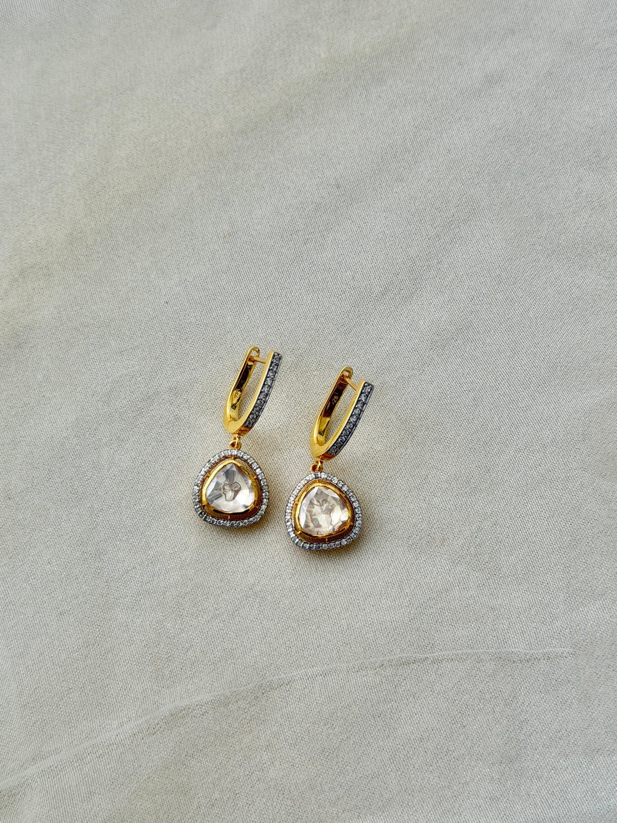 Tilak Earrings featuring clear triangular drops with sparkling stone borders suspended from gold-tone hoops.