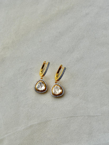 Tilak Earrings featuring clear triangular drops with sparkling stone borders suspended from gold-tone hoops.
