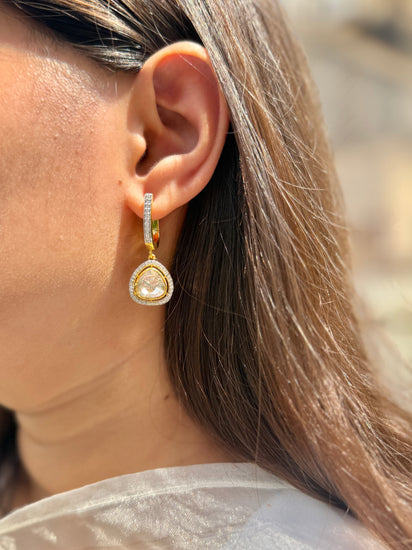 Tilak Earrings featuring clear triangular drops with sparkling stone borders suspended from gold-tone hoops.