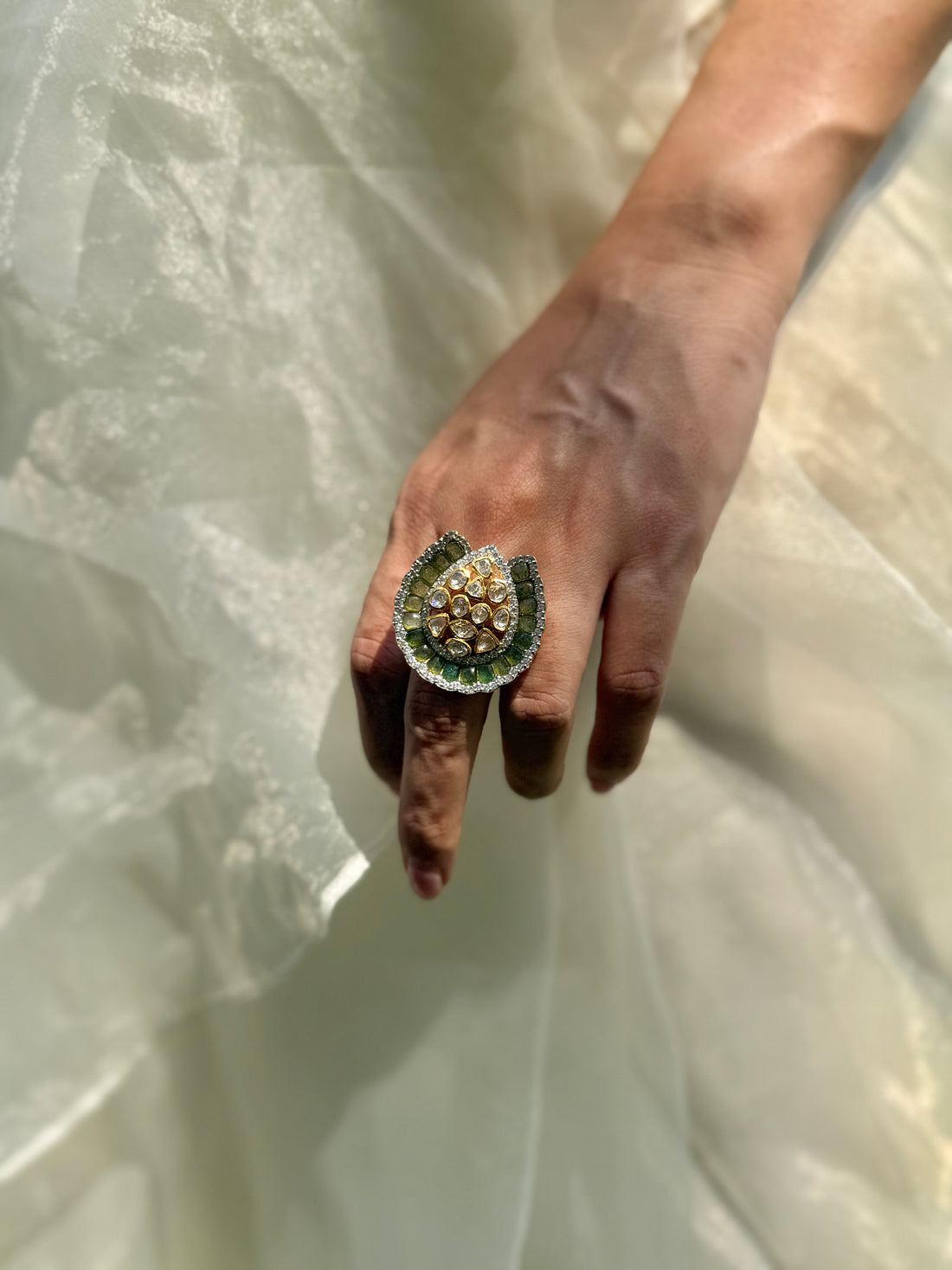 Dua Ring featuring a clear-stone cluster surrounded by a curved dark green border in a gold-tone setting.