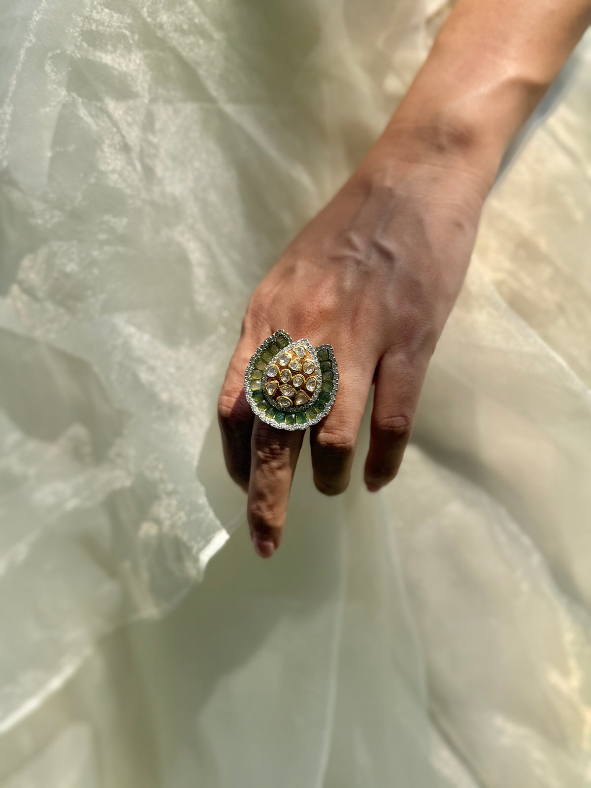 Dua Ring featuring a clear-stone cluster surrounded by a curved dark green border in a gold-tone setting.