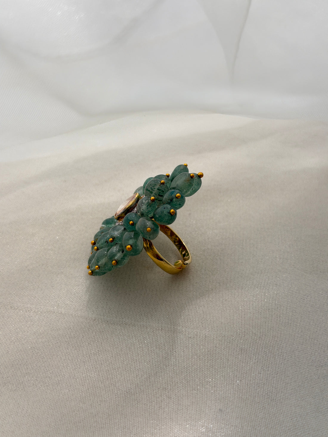 Trisha Ring featuring green oval beads arranged in a floral design around a clear triangular centre.