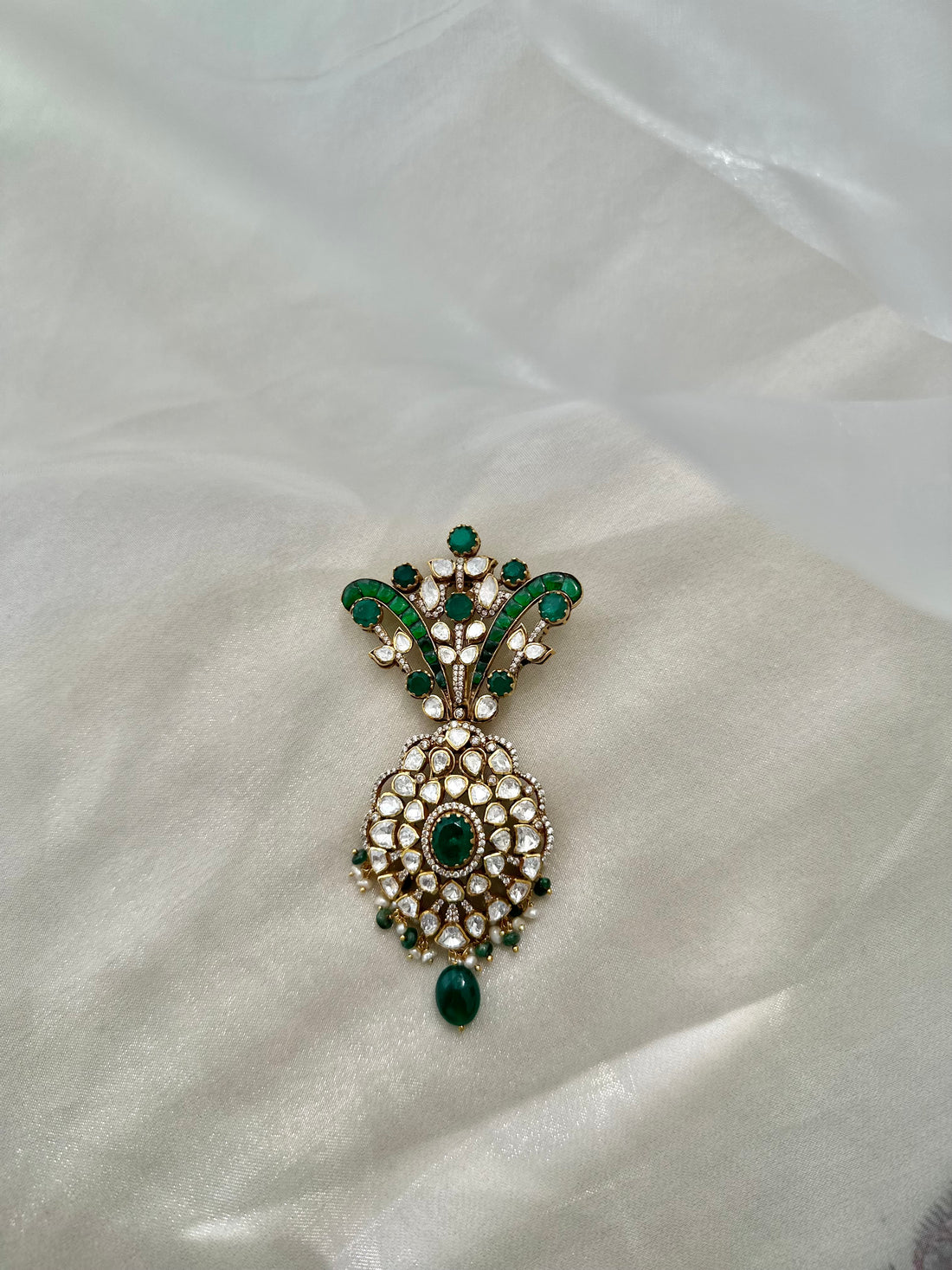 Kochi Brooch featuring green accents, clear-stone detailing and a dangling green bead in an ornate gold-tone setting.