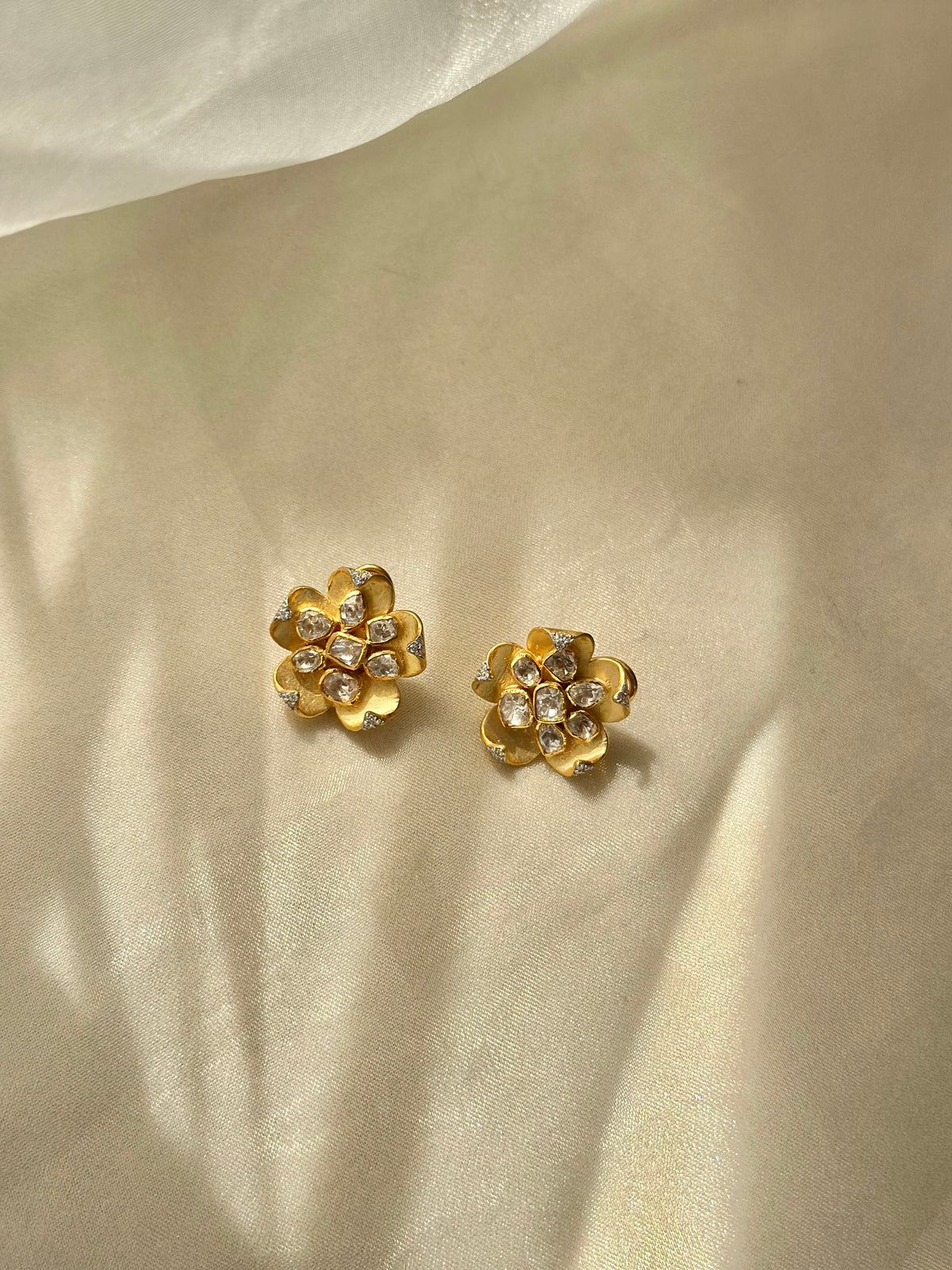 Kusum Polki Earrings featuring sculpted gold-tone flower petals with clustered clear-stone centres.